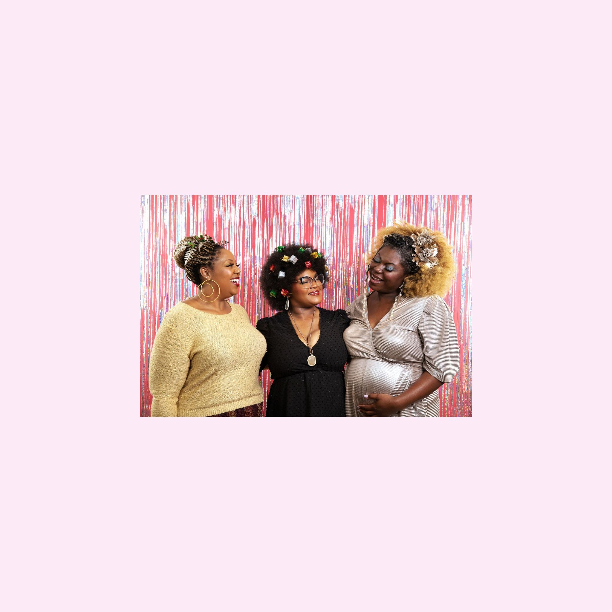 Jasmine, Jae and Madia looking at each other wearing sparkly tops and standing in front of a pink metallic wall of fringe