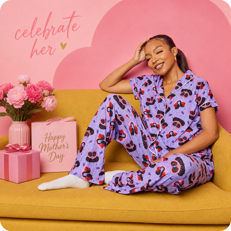 Woman in a purple pajama set with animal print sitting on a yellow couch with Mother's Day decorations.