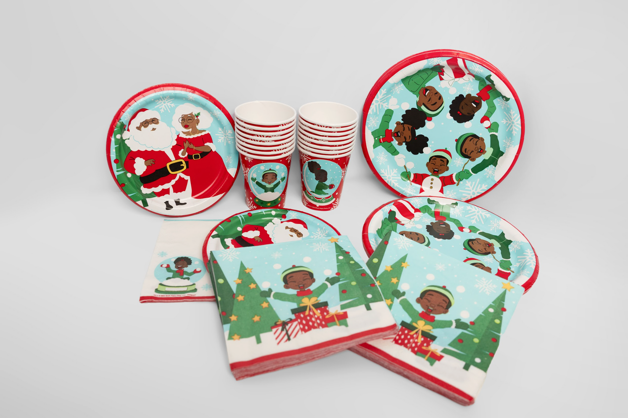 Christmas-themed paper plates, cups, and napkins with black characters on a white background.