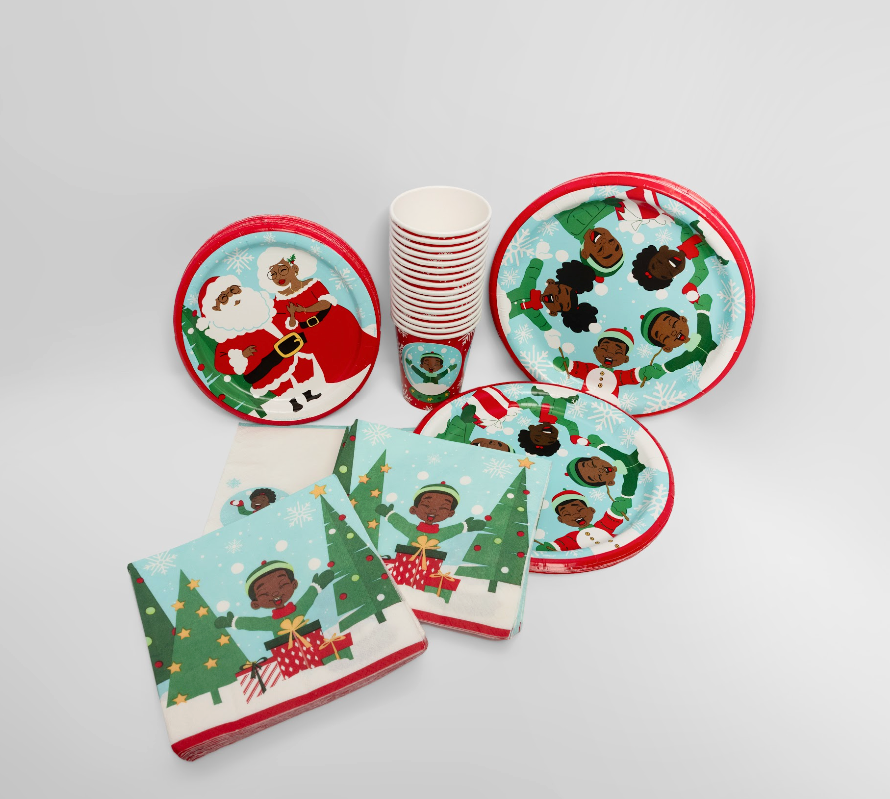 Christmas-themed paper plates, cups, and napkins with multicultural characters on a white background.