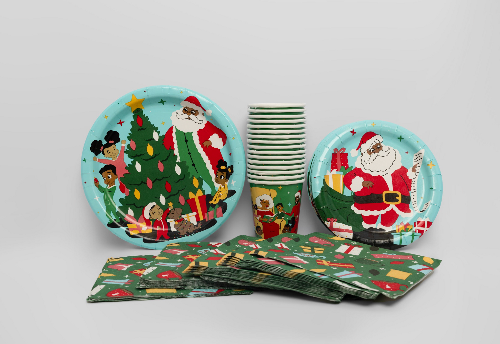 Christmas-themed paper plates, cups, and napkins on a light gray background