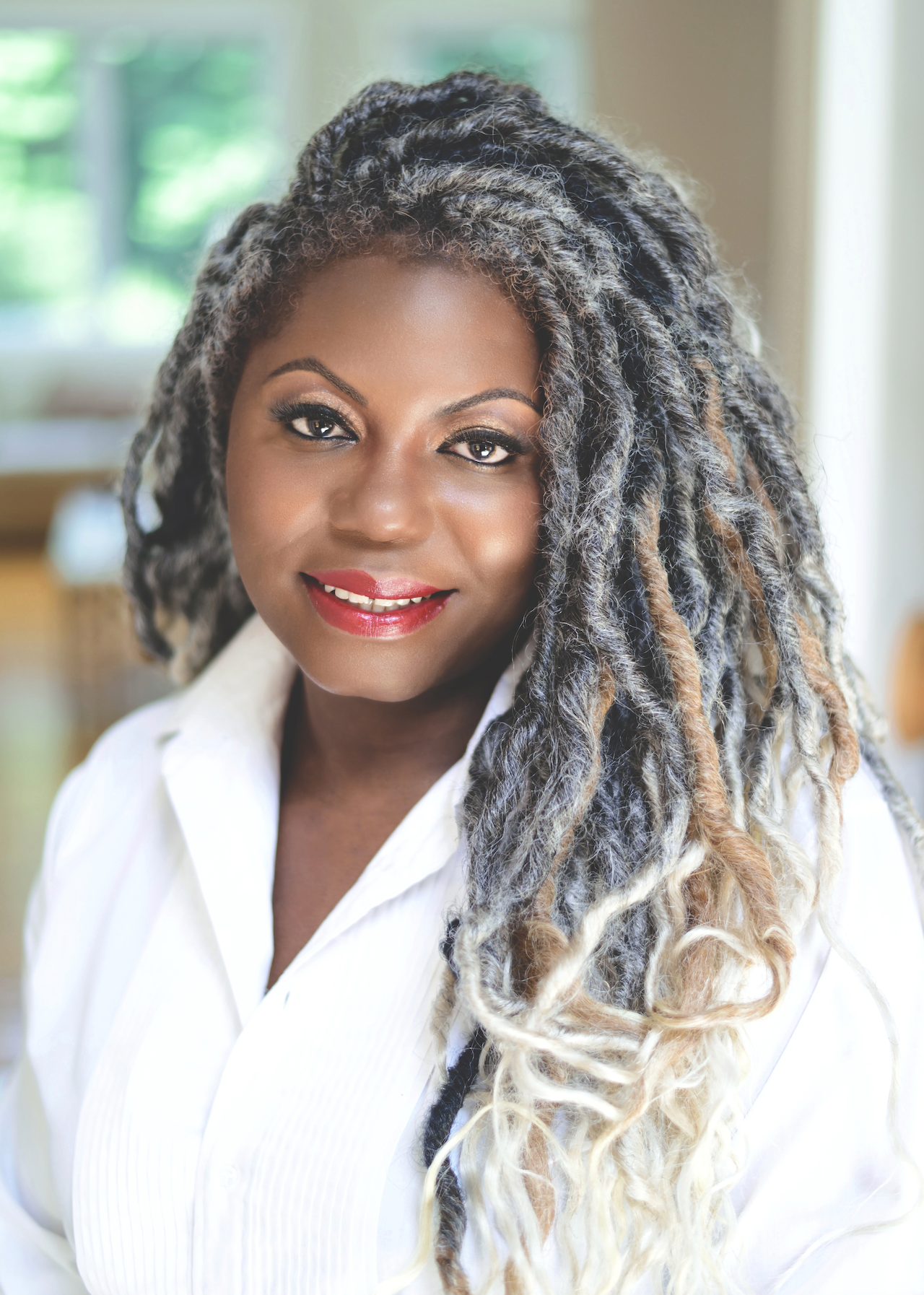 Madia Willis CEO of Black Paper Party in a white shirt with her hair styled in locs