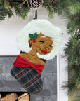 Nana Klaus Noire Noel plaid holiday stocking hanging by a fireplace.
