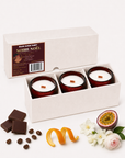 Noire Noel candle gift set in an open box with chocolate, fruit and coffee fragrance props.