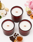 Overhead view of three Noire Noel candles with wood wicks and fragrance-inspired props.
