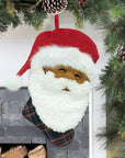 Papa Klaus Noire Noel plaid holiday stocking hanging by a fireplace.