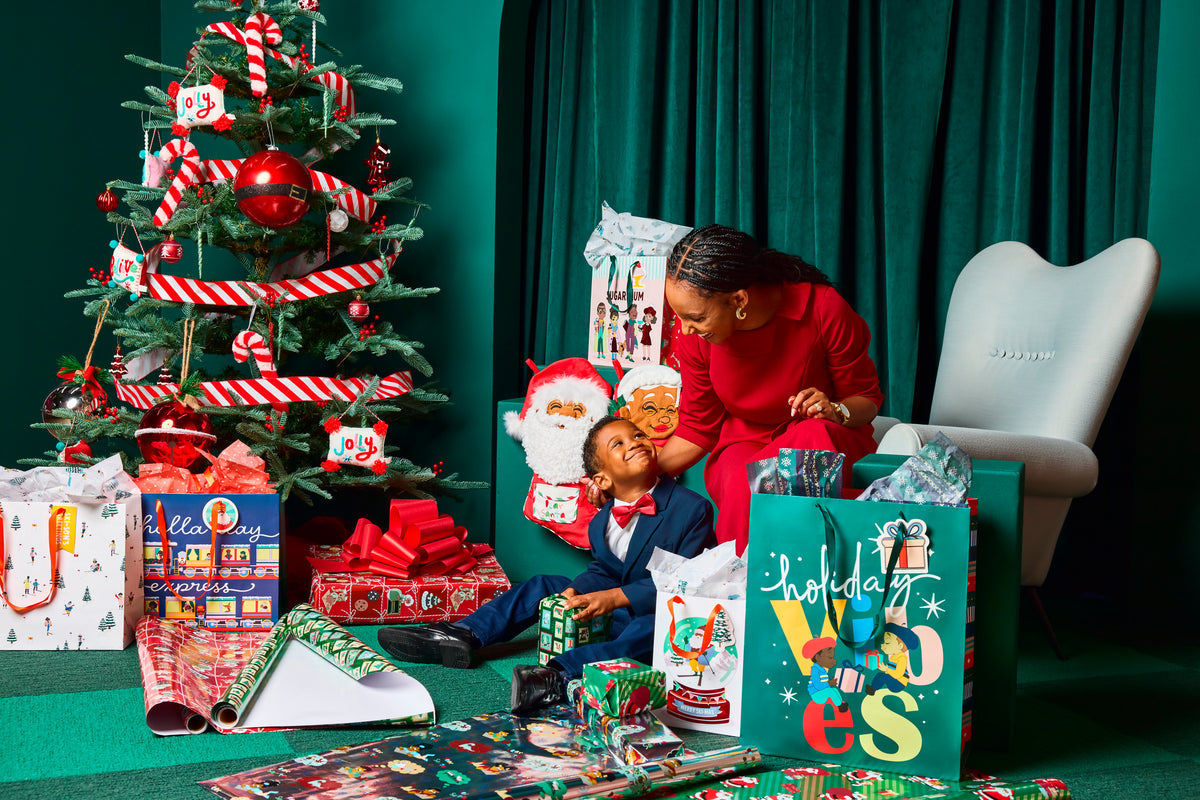 Black Paper Party holiday scene with a mother and child surrounded by gifts and festive decor.