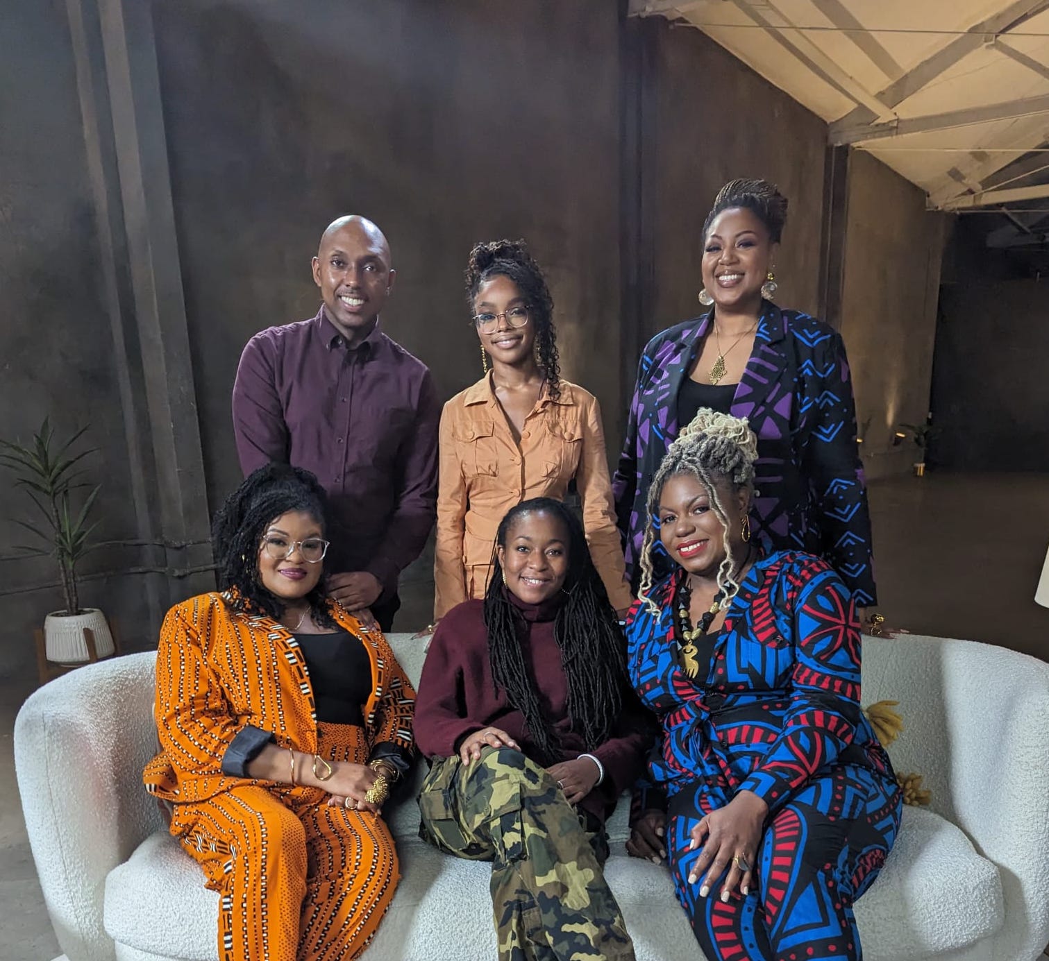 A group of black entreprenuers sitting on and standing around a white boucle couch alongside. Include Marsai Martin, Jasmine, Jae, and Madia